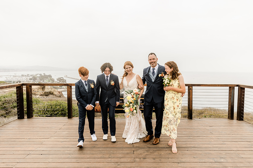  whimsical wedding at an ocean front venue with the groom in a mix and match look with navy and grey colors – couple with family