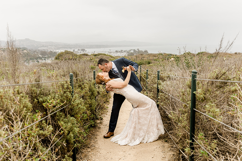  whimsical wedding at an ocean front venue with the groom in a mix and match look with navy and grey colors – couple kissing