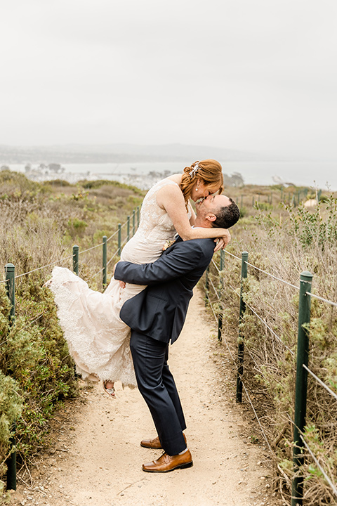  whimsical wedding at an ocean front venue with the groom in a mix and match look with navy and grey colors – couple in the flowers 