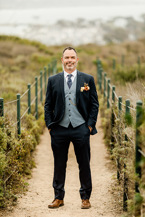  whimsical wedding at an ocean front venue with the groom in a mix and match look with navy and grey colors – groom