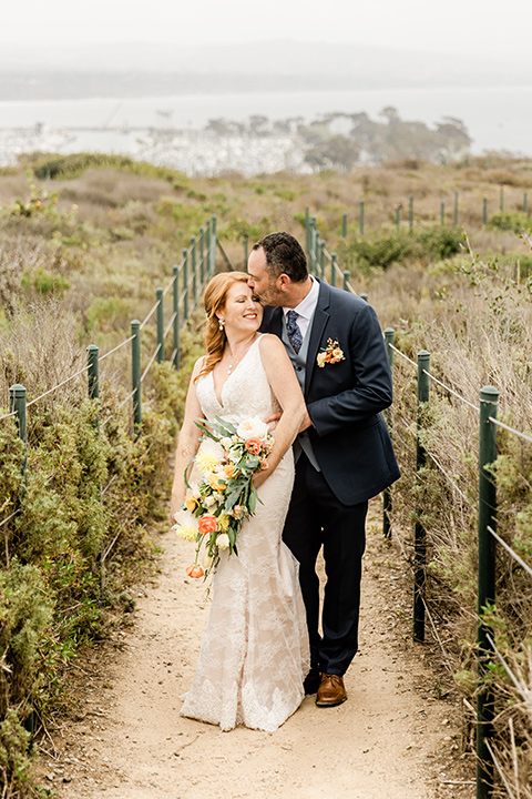  whimsical wedding at an ocean front venue with the groom in a mix and match look with navy and grey colors – couple in the flowers