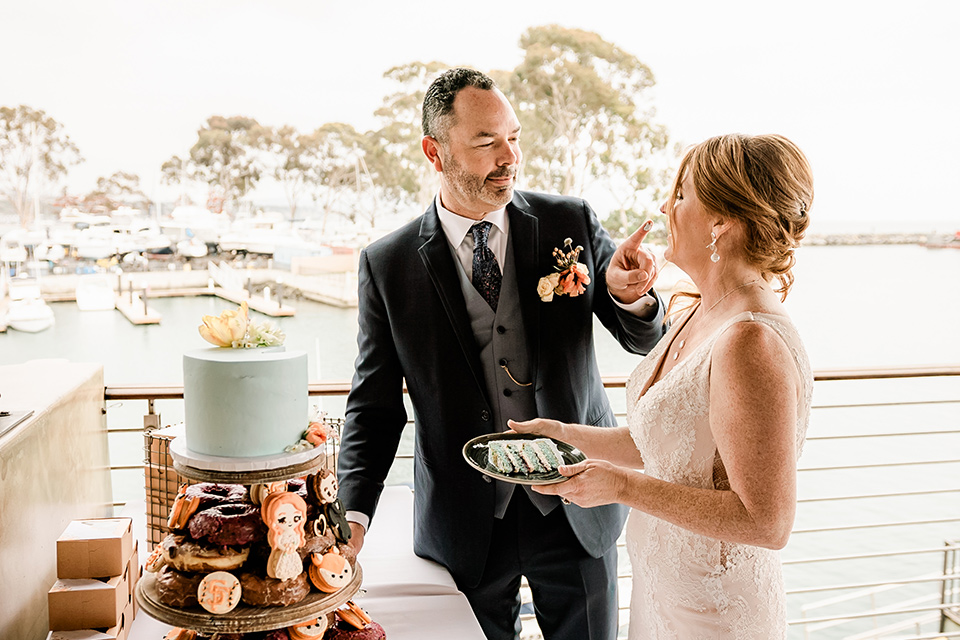 whimsical wedding at an ocean front venue with the groom in a mix and match look with navy and grey colors – cutting the cake
