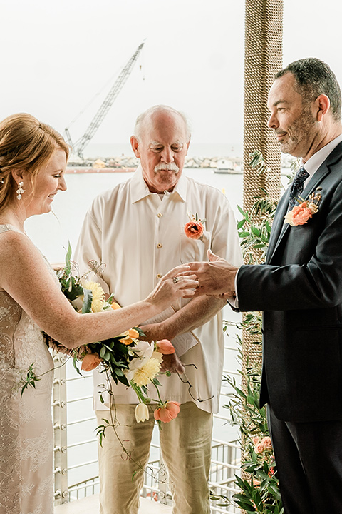  whimsical wedding at an ocean front venue with the groom in a mix and match look with navy and grey colors – couple at ceremony