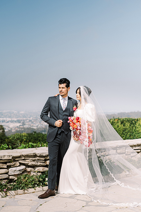  a Chinese-Spanish fusion wedding with the bride in a white flowing gown and the groom in a grey suit and burgundy velvet coat - couple outside 