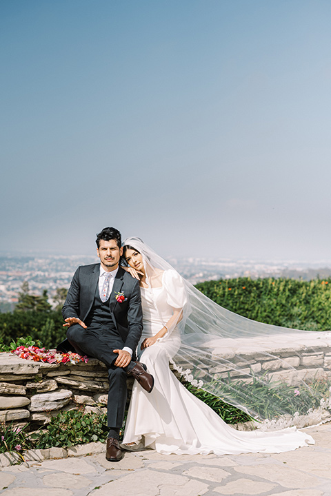  a Chinese-Spanish fusion wedding with the bride in a white flowing gown and the groom in a grey suit and burgundy velvet coat - couple outside 
