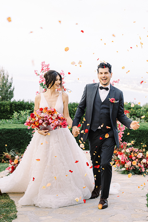  a Chinese-Spanish fusion wedding with the bride in a white flowing gown and the groom in a grey suit and burgundy velvet coat - walking down the aisle 