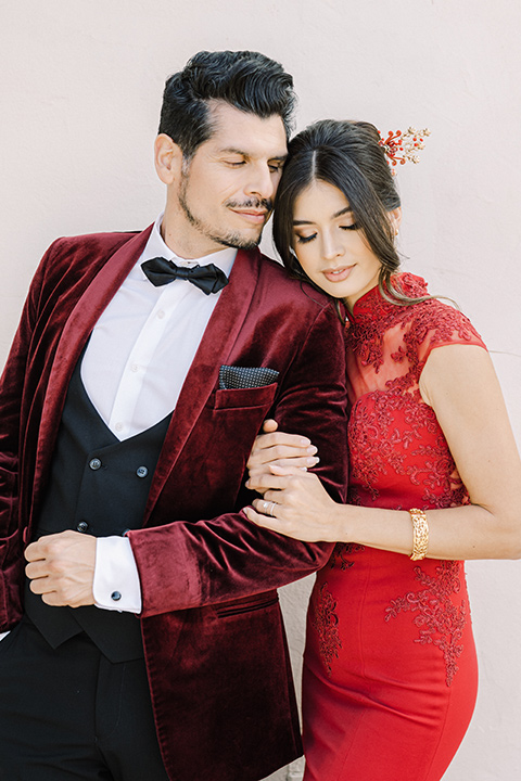  a Chinese-Spanish fusion wedding with the bride in a white flowing gown and the groom in a grey suit and burgundy velvet coat - couple in red looks 