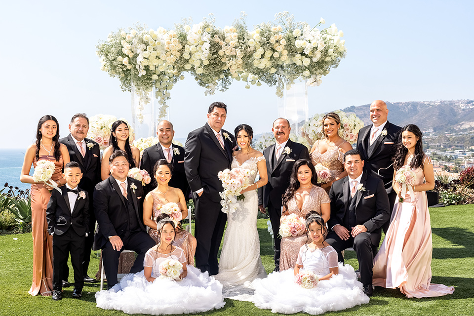  glitz and glam wedding by the beach with the bride in a lace crystal gown and the groom in a black tuxedo – group photo with the bridesmaids and groomsmen