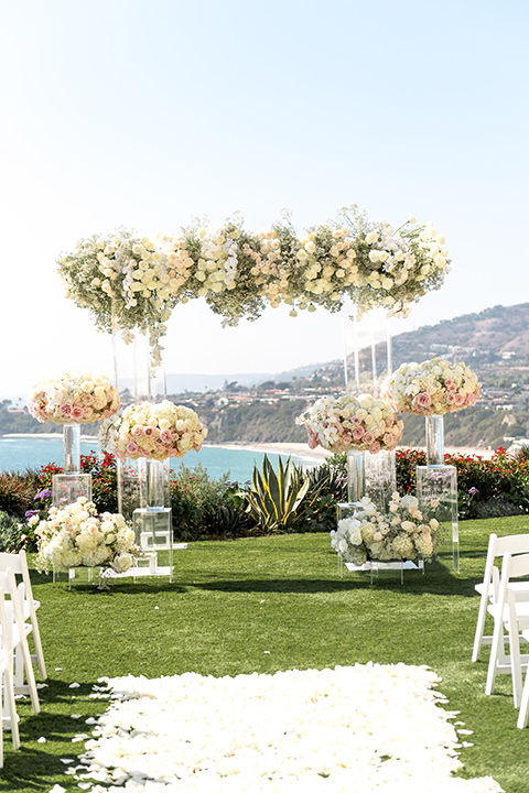  glitz and glam wedding by the beach with the bride in a lace crystal gown and the groom in a black tuxedo – ceremony altar