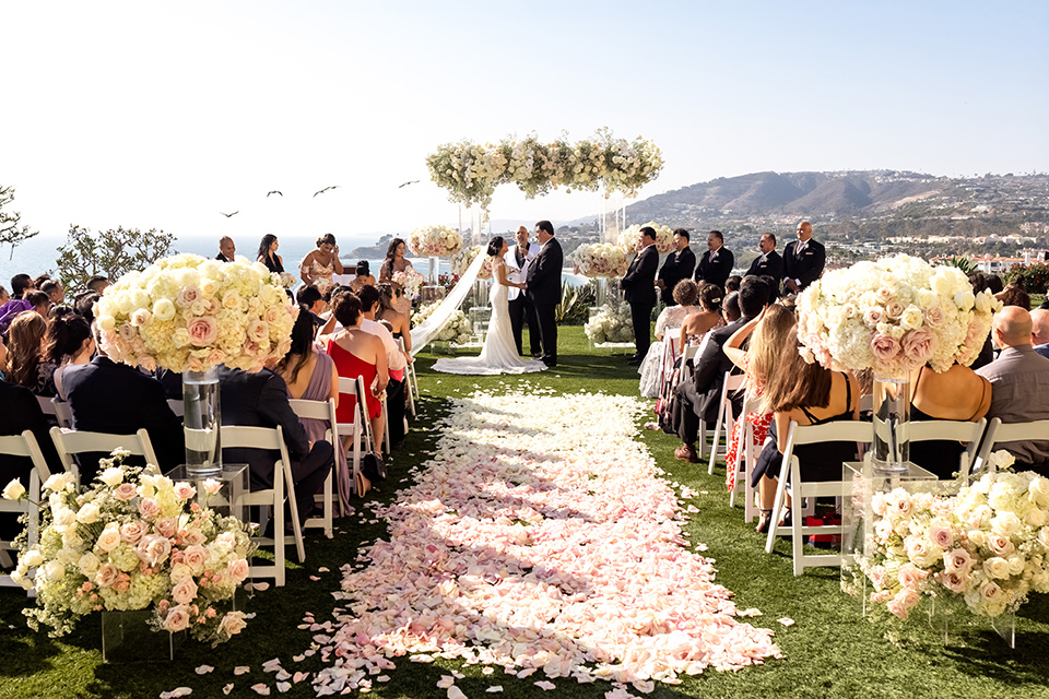  glitz and glam wedding by the beach with the bride in a lace crystal gown and the groom in a black tuxedo – ceremony