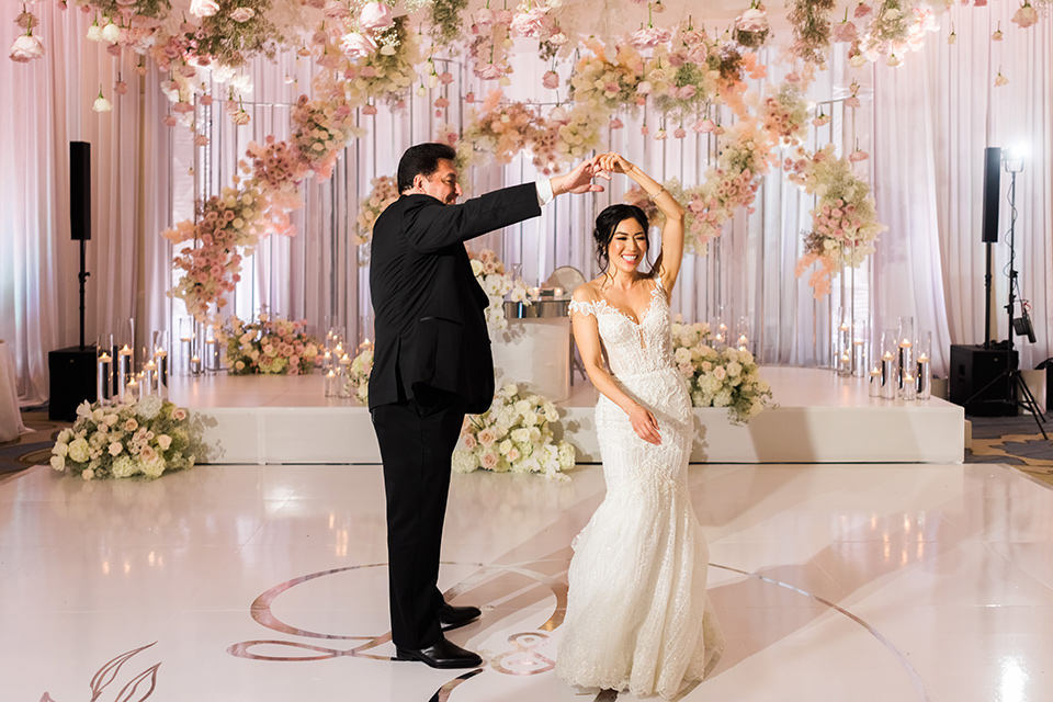  glitz and glam wedding by the beach with the bride in a lace crystal gown and the groom in a black tuxedo – first dance