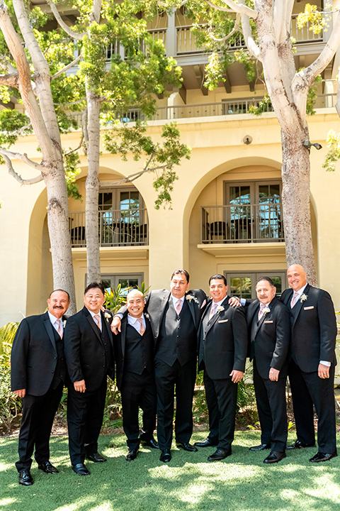  glitz and glam wedding by the beach with the bride in a lace crystal gown and the groom in a black tuxedo – groomsmen