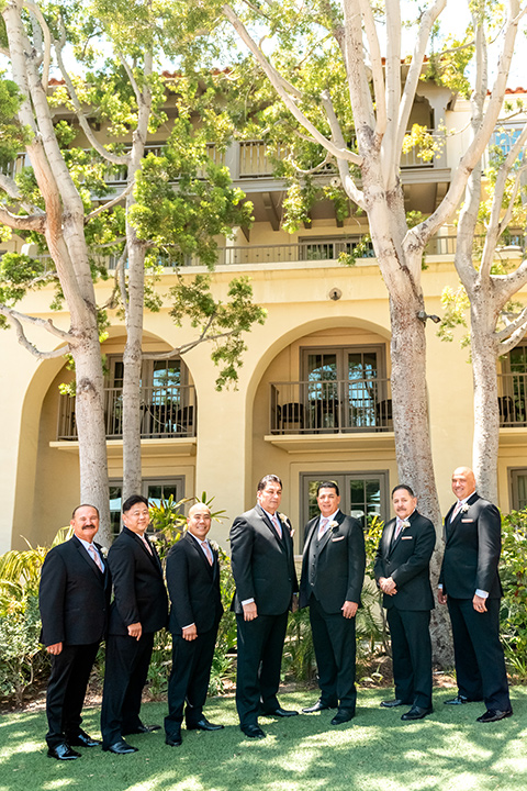  glitz and glam wedding by the beach with the bride in a lace crystal gown and the groom in a black tuxedo – groomsmen