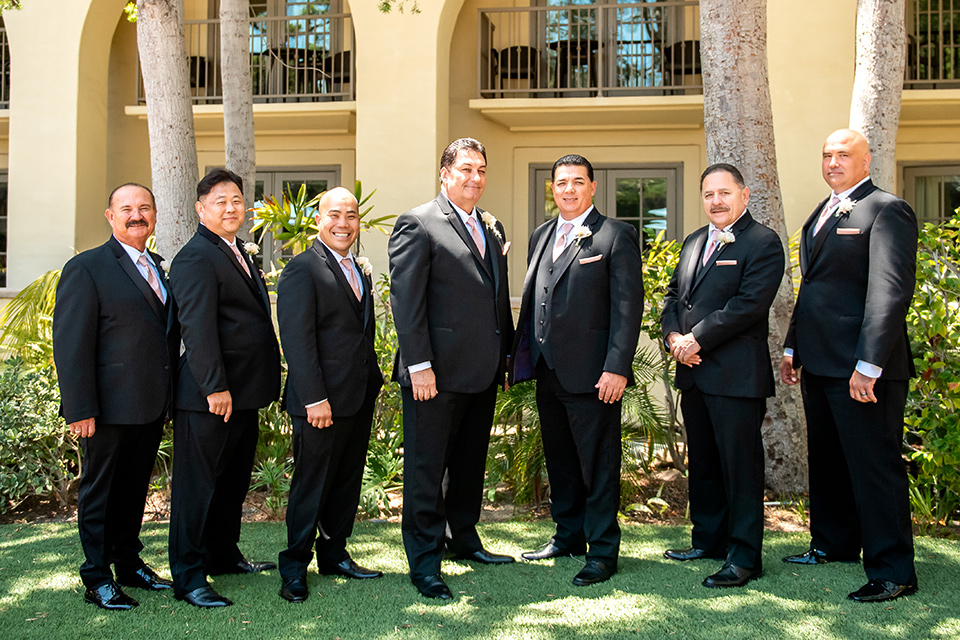  glitz and glam wedding by the beach with the bride in a lace crystal gown and the groom in a black tuxedo – groomsmen