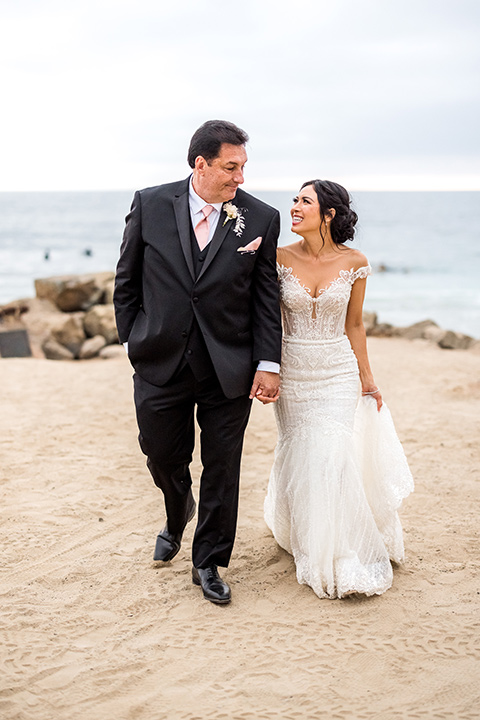  glitz and glam wedding by the beach with the bride in a lace crystal gown and the groom in a black tuxedo – couple on the cliffs 