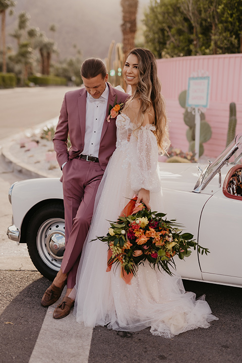  a funky groovy downtown palm springs wedding with bright colors and boho style - couple by the car 