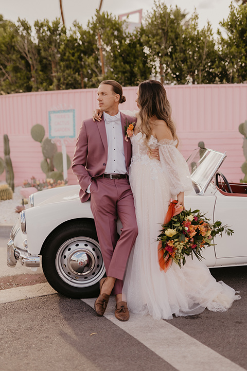  a funky groovy downtown palm springs wedding with bright colors and boho style - couple by the car 