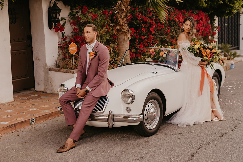  a funky groovy downtown palm springs wedding with bright colors and boho style - couple in front of car 