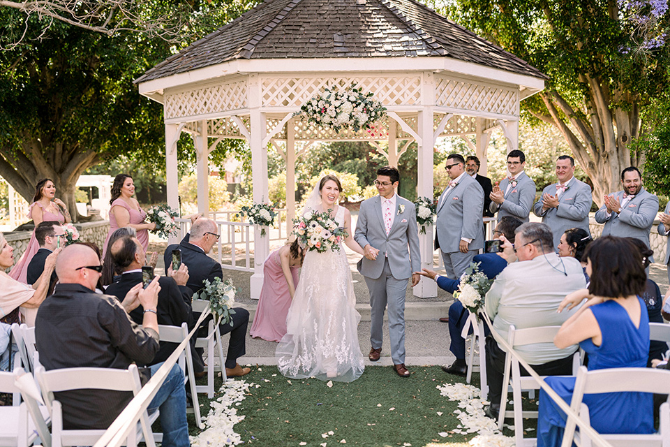  a romantic garden wedding with grey and pink décor and style, with the bride in a gorgeous white gown and the groom in a heather grey suit, the bridesmaids were in blush pink gowns and the groomsmen in heather grey suits – walking down the aisle