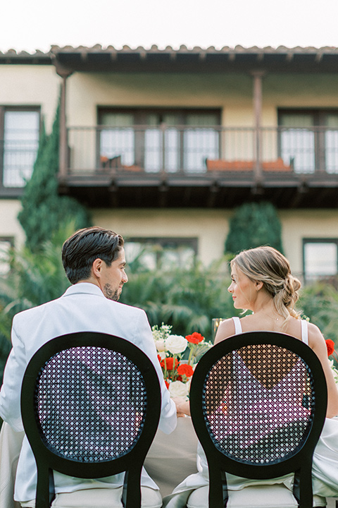  modern white and black wedding with pops of red – couple at the reception table 