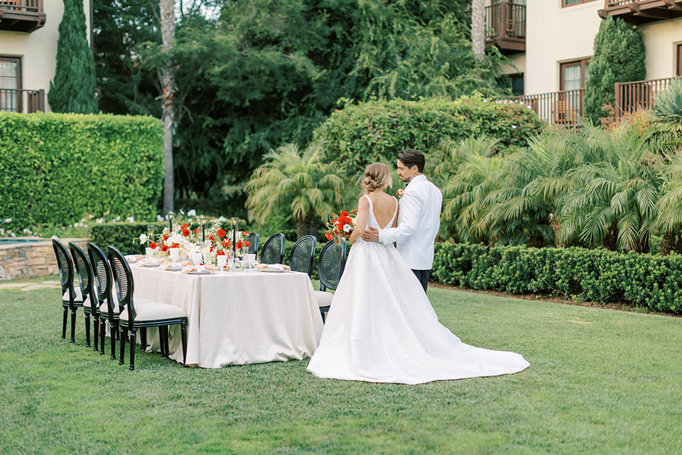  modern white and black wedding with pops of red – couple sitting at the reception table
