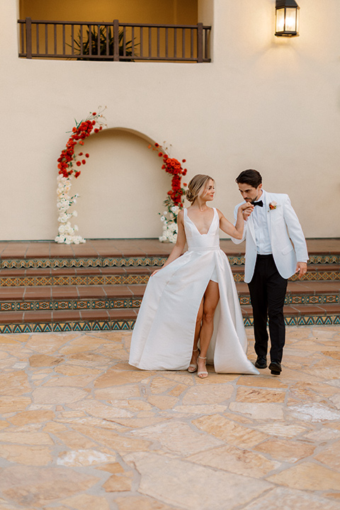  modern white and black wedding with pops of red – couple kissing down the aisle 