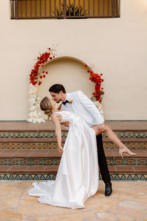  modern white and black wedding with pops of red – couple kissing down the aisle 