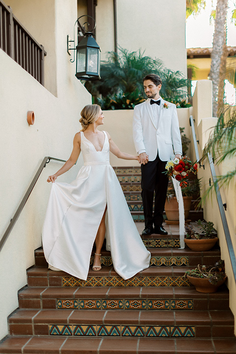  modern white and black wedding with pops of red – couple walking down the stairs 