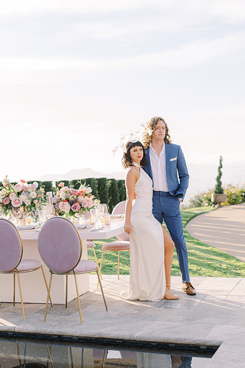  feminine spring editorial at a villa and the groom in a steel blue suit – couple by tables 