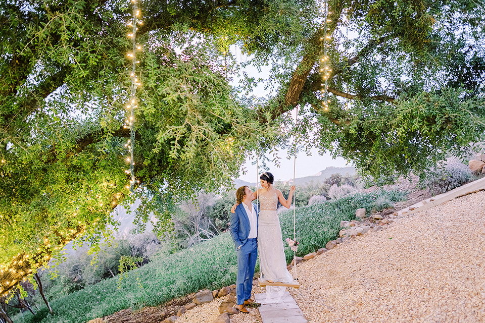  feminine spring editorial at a villa and the groom in a steel blue suit – couple on the swing 