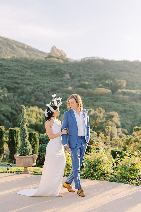  feminine spring editorial at a villa and the groom in a steel blue suit – couple walking on the mountains 