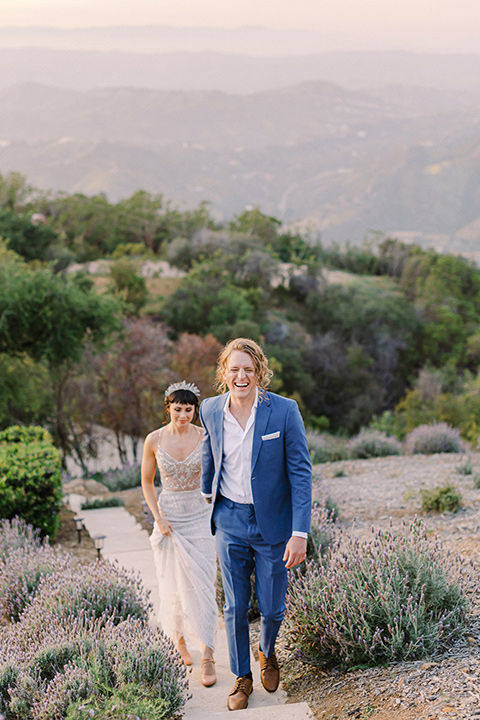  feminine spring editorial at a villa and the groom in a steel blue suit – couple walking on the mountains 