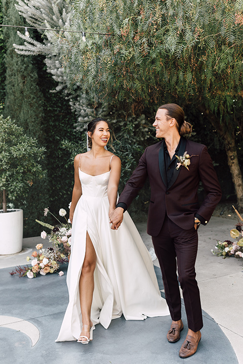  fig house shoot with burgundy and yellow details and the groom in a burgundy tuxedo – couple walking 