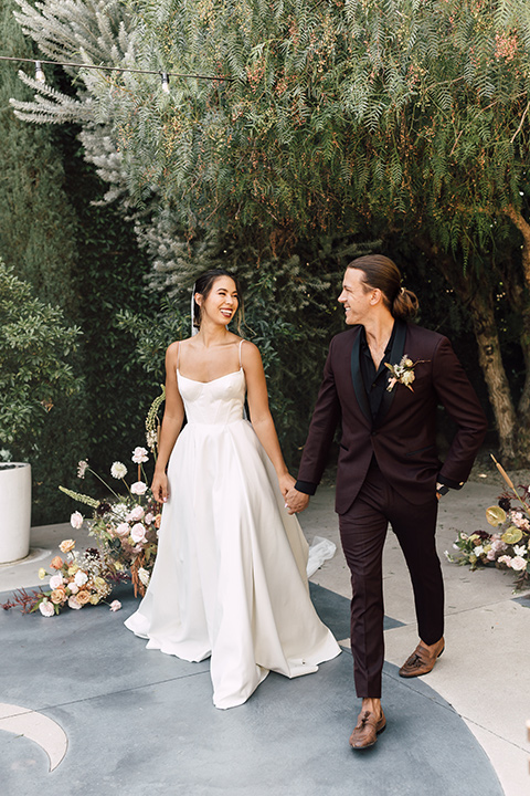  fig house shoot with burgundy and yellow details and the groom in a burgundy tuxedo – couple walking 