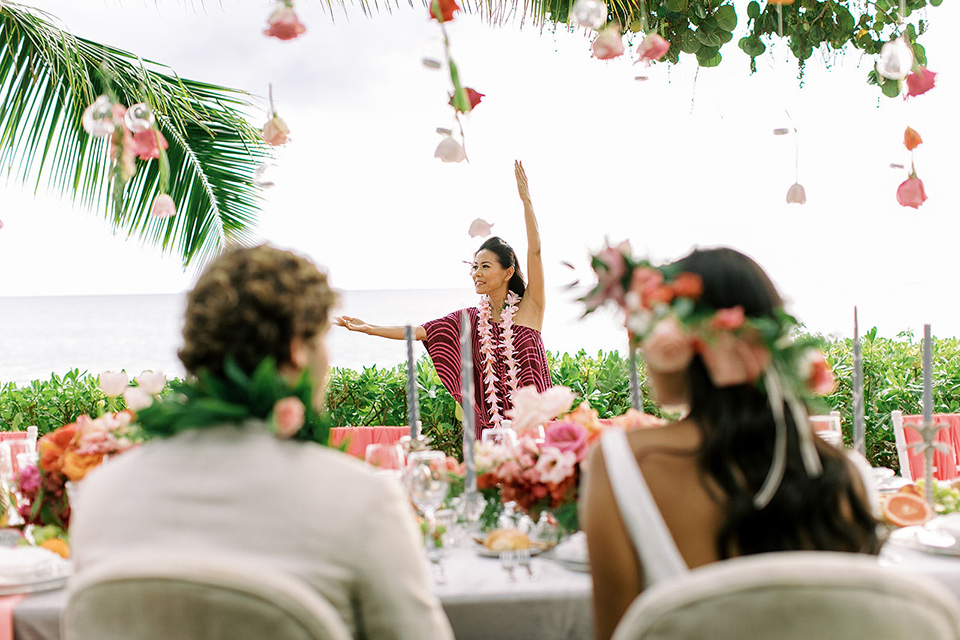  tropical tan and berry colored wedding in Hawaii – couple watching Hawaiian dancer 