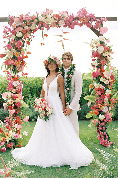  tropical tan and berry colored wedding in Hawaii – couple at ceremony arch 