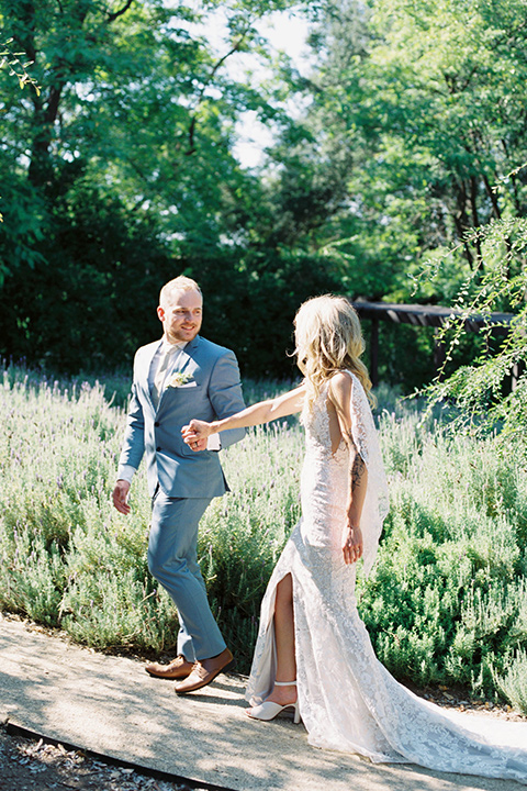  light blue and pink wedding with the groom in a light blue suit and the bride in a lace gown – couple walking down the aisle 