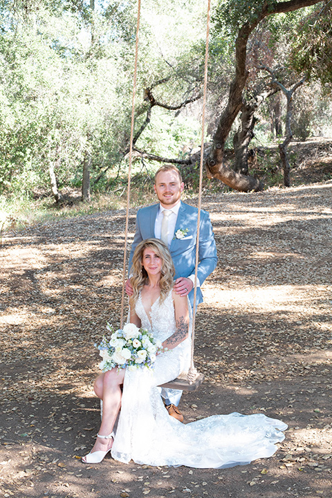  light blue and pink wedding with the groom in a light blue suit and the bride in a lace gown – couple on the swings 