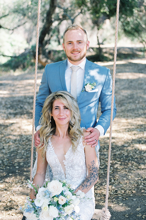  light blue and pink wedding with the groom in a light blue suit and the bride in a lace gown – couple on the swings 