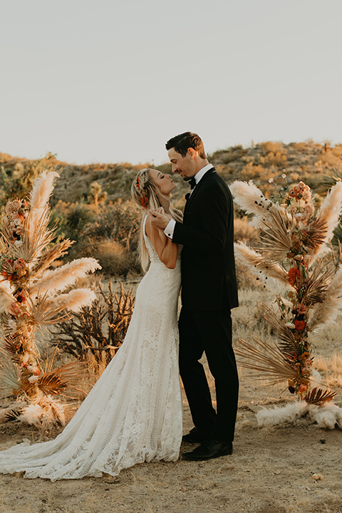  joshua tree wedding with the groom in a gold velvet tuxedo and a black tuxedo and the bride in a flowing gown with bridal wings – first kiss