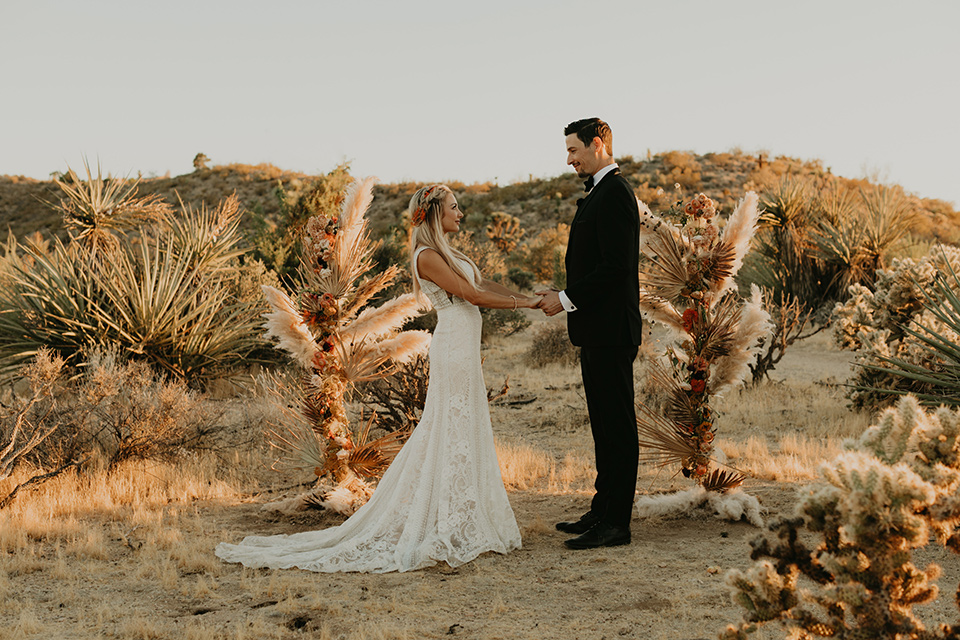  joshua tree wedding with the groom in a gold velvet tuxedo and a black tuxedo and the bride in a flowing gown with bridal wings – vows 