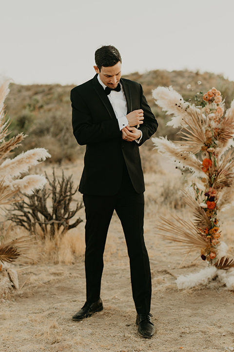  joshua tree wedding with the groom in a gold velvet tuxedo and a black tuxedo and the bride in a flowing gown with bridal wings – groom