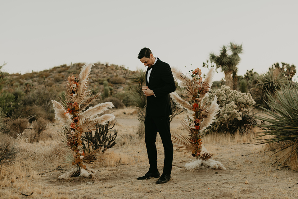  joshua tree wedding with the groom in a gold velvet tuxedo and a black tuxedo and the bride in a flowing gown with bridal wings – groom