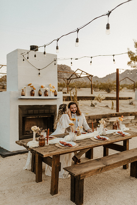  a dessert wedding in Joshua tree shown two ways: a modern black and white theme and a neutral gold and tan theme – groom in ivory paisley tuxedo and bride at sweetheart table 
