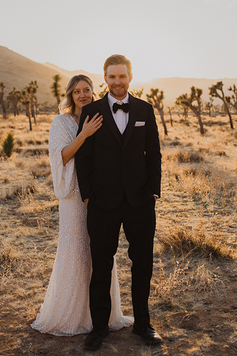  Joshua tree elopement with the bride in a sparkly gown and the groom in a black tuxedo – bride holding the groom