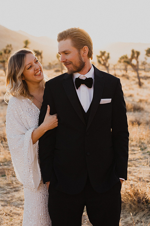  Joshua tree elopement with the bride in a sparkly gown and the groom in a black tuxedo– bride holding the groom 