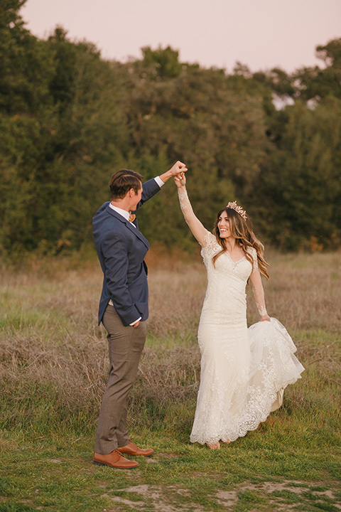  fairytale wedding in the meadow with the bride in a lace long sleeve gown and the groom in a slate blue and café brown look – bride and groom dancing 