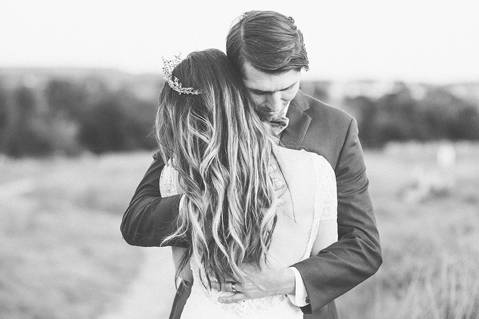  fairytale wedding in the meadow with the bride in a lace long sleeve gown and the groom in a slate blue and café brown look – bride and groom hugging 