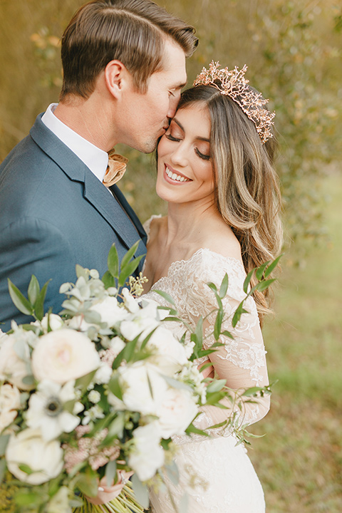  fairytale wedding in the meadow with the bride in a lace long sleeve gown and the groom in a slate blue and café brown look – bride and groom close together 