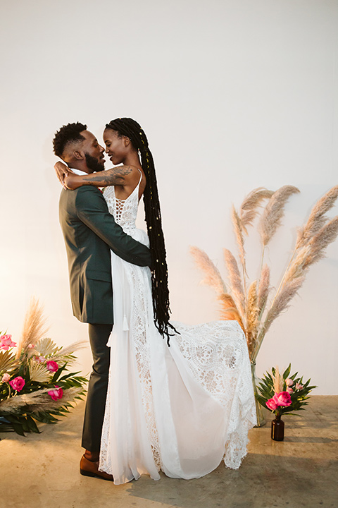  a chic LA studio shoot for a modern boho wedding – with the groom in a white lace gown and the groom in a green suit – bride and groom at the altar